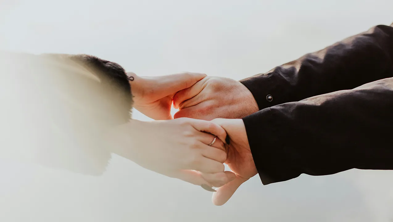 Due persone si tengono per me mani in un gesto di connessione e sostegno reciproco.