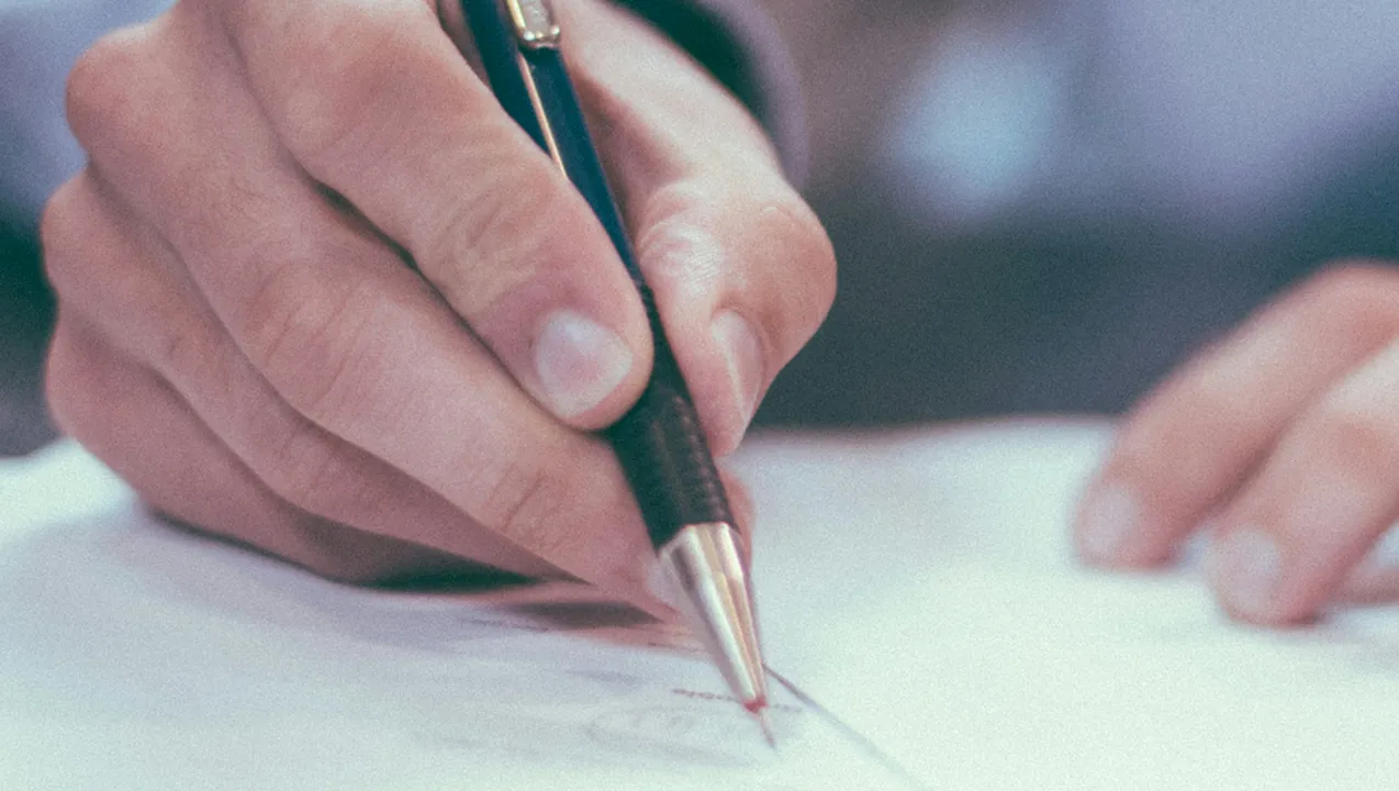 Mano di una persona che firma un documento con una penna a sfera, su un foglio bianco, in un contesto professionale.